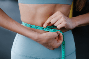 Woman measuring stomach with tape measure