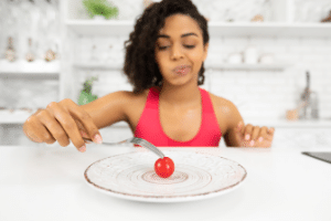 Woman on a diet looking at a small tomato