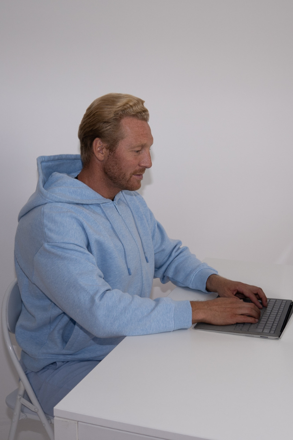 Man in front of laptop wearing Prime Science Calorie Burner Vest under hoodie